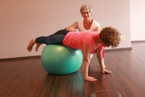 1fach Yoga | 1fach Gesund - Studio in 64572 Büttelborn - Silke Wagner mit Kundin auf dem Ball
